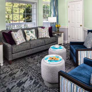 A cozy living room with a grey sofa, blue armchairs, and decorative elements.