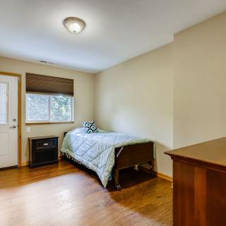 A minimalist bedroom with a single bed and hardwood flooring.