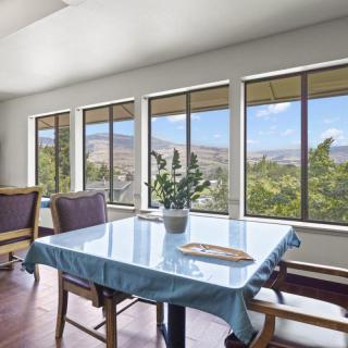 A bright dining room with a table and chairs, featuring large windows with a scenic view.