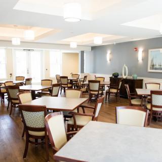 A modern dining room with neatly arranged tables and chairs, featuring elegant lighting.