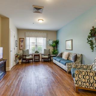 A cozy living room with a sofa, chairs, and hardwood flooring.