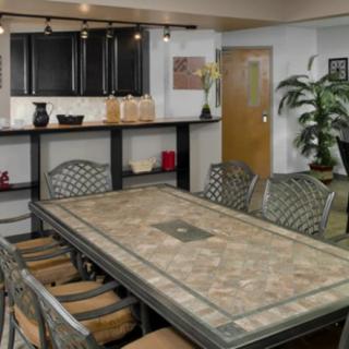 A modern dining room with a large rectangular table and chairs, adjacent to an open kitchen area with contemporary decor.