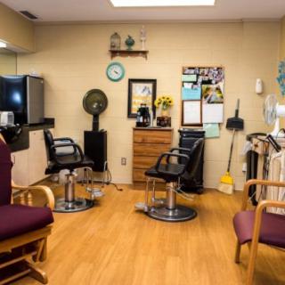 A cozy hair salon interior with styling chairs, mirrors, and various equipment.