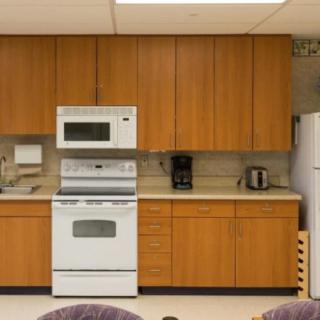 A kitchen with wooden cabinets, featuring a stove, microwave, coffee maker, and toaster.