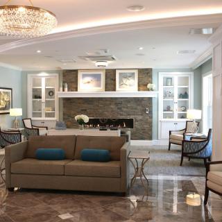 A modern and cozy living room featuring a comfortable sofa, elegant fireplace, and stylish chandelier.