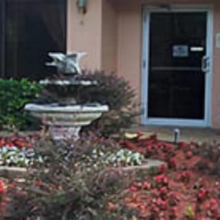 A small fountain surrounded by flowers near a building entrance.