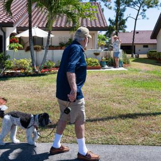 A man walks his dog on a leash through a suburban neighborhood.