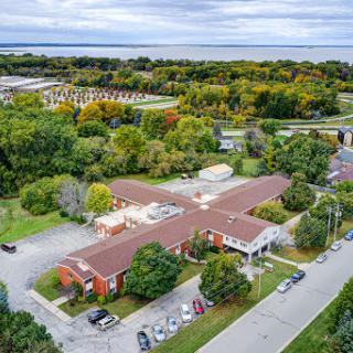 An aerial view showcasing a building surrounded by lush greenery and a glimpse of water in the background.