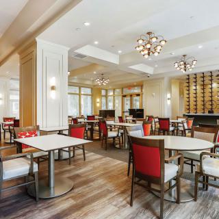 A modern restaurant interior with elegantly arranged tables and chairs, featuring stylish lighting fixtures.