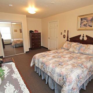 A cozy bedroom with a neatly made bed, wooden furniture, and decorative elements.
