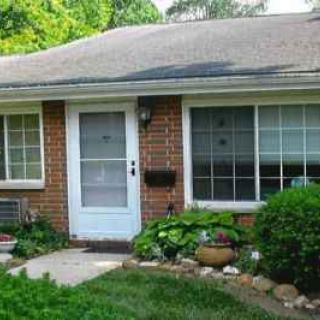 A small brick house with a front garden and large windows.