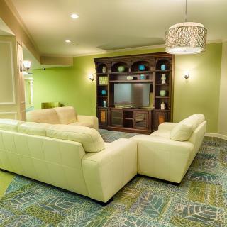 A cozy and modern living room with green walls, a large sectional sofa, and a television entertainment center.