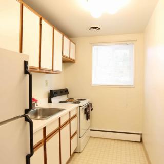 A small, bright apartment kitchen with white cabinets and appliances.