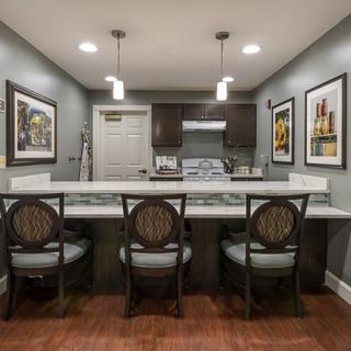 A modern kitchen with a counter and bar stools, featuring pendant lights and artwork on the walls.