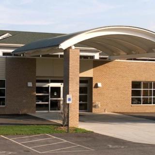 A modern school building with a prominent entrance and arched roof design.