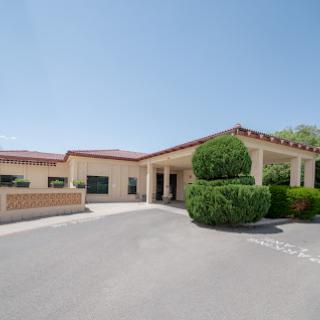 A modern building with well-maintained landscaping under a clear blue sky.