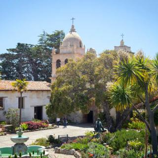 A historic mission building with a garden and fountain in California.