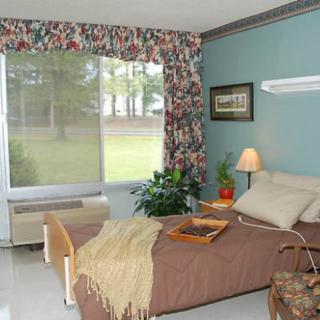 A cozy hospital room with a single bed, decorative curtains, and natural light streaming through the large window.