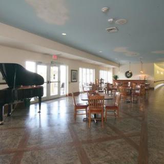 A spacious dining area with a grand piano and several tables and chairs.