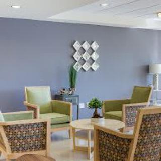 A modern lounge area featuring comfortable chairs, a coffee table, and decorative wall art.