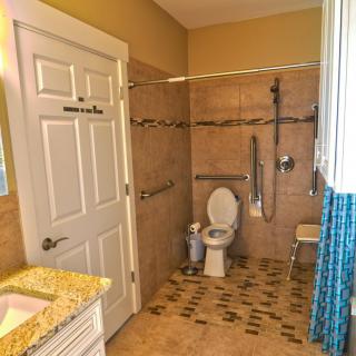 An accessible bathroom with a toilet, shower, and grab bars for safety.