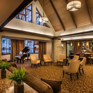 A modern hotel lobby featuring a grand piano and comfortable seating arrangements under warm ambient lighting.