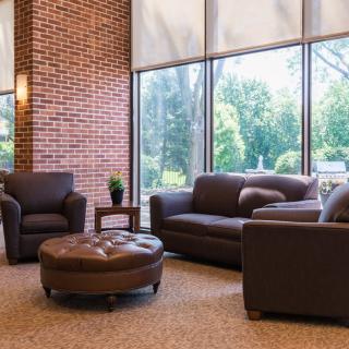 A cozy lounge area with leather furniture and large windows letting in natural light.