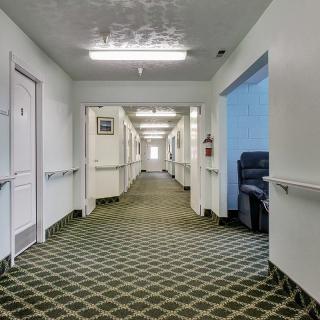 An empty hallway with patterned carpet and several doors along the sides.
