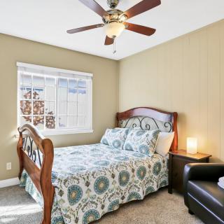 A cozy bedroom featuring a wooden bed with patterned bedding, a bedside lamp, and a ceiling fan.
