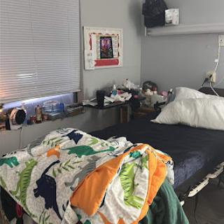 A cozy bedroom setup featuring a bed with colorful blankets and decorative elements.