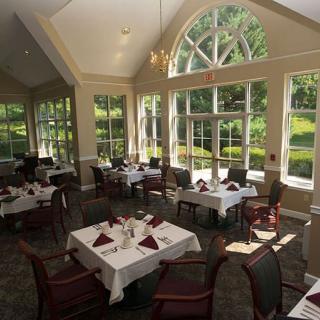 A spacious dining room with elegantly set tables and large windows letting in natural light.