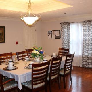 A neatly set dining room with a large table, chairs, and a chandelier above.