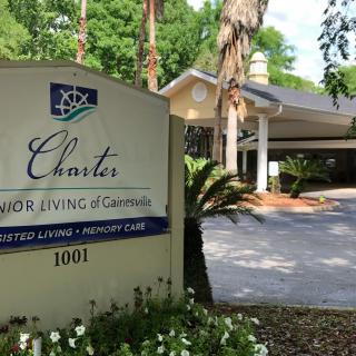 Entrance sign for a senior living community surrounded by trees and landscaping.
