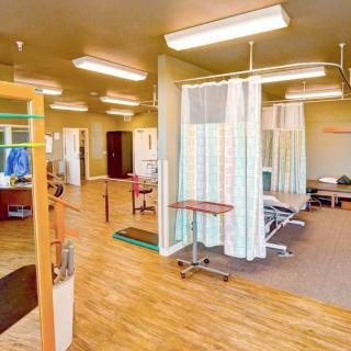 Interior view of a medical facility with examination beds and privacy curtains.