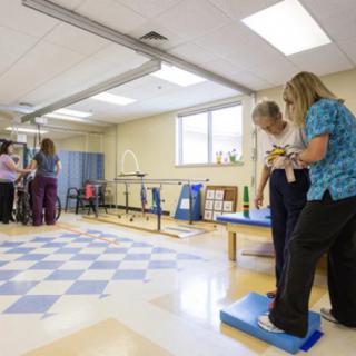 A rehabilitation session taking place in a physical therapy room with patients and therapists.