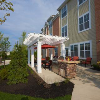 A modern apartment complex featuring an outdoor pergola with comfortable patio seating and landscaping.