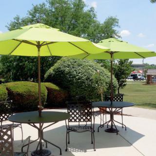 Outdoor patio area with green umbrellas and metal furniture on a sunny day.
