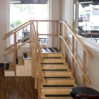 Indoor wooden stairs with railings, commonly used for physical therapy or exercise.