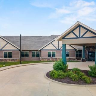 A modern building with a wide driveway and well-maintained landscaping at the entrance.