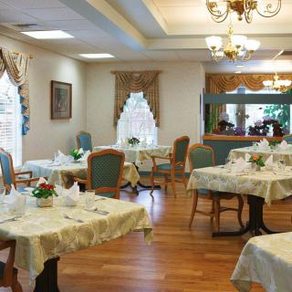 An elegant dining room with tables set for guests, featuring classic decor and chandeliers.