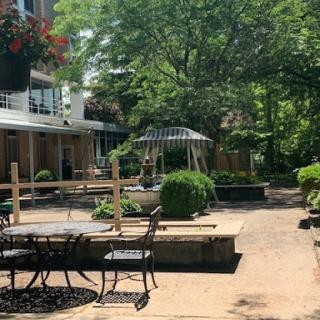 A serene outdoor garden space featuring tables and lush greenery.
