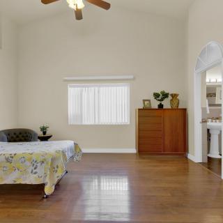 A minimalist bedroom with hardwood flooring and simple furnishings.