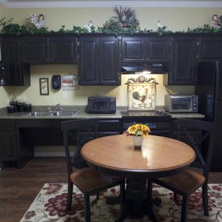 A cozy kitchen setting featuring dark cabinets, a round dining table with chairs, and decorative elements.