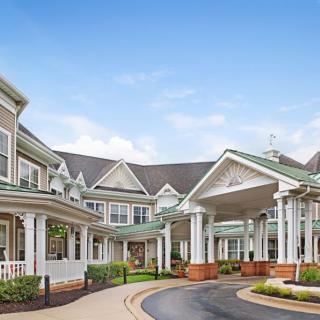 A large residential building with a covered entrance and landscaped surroundings.