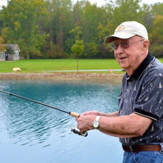 A joyful senior man enjoying a peaceful day fishing by the lake.