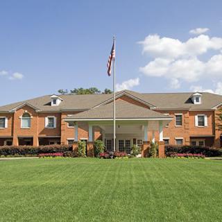 A large building with a manicured lawn and a flag flying at the entrance.