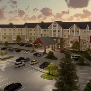 A large residential complex with a spacious parking lot, set against a picturesque sunset.