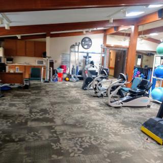 A spacious indoor gym area featuring various exercise machines and fitness equipment.