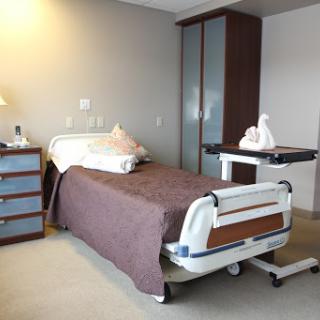 A well-equipped hospital patient room featuring a bed, nightstand, and storage.