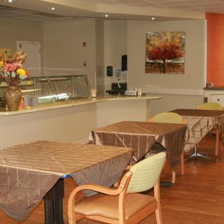 A cozy cafe interior with neatly arranged tables and chairs, featuring a decorative painting on the wall.